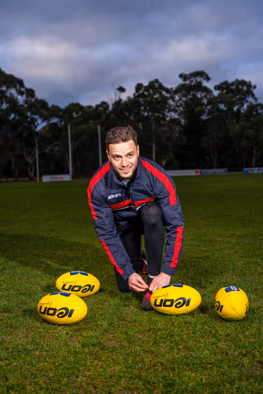 Athlete wearing an Icon training jacket on the field with yellow footballs