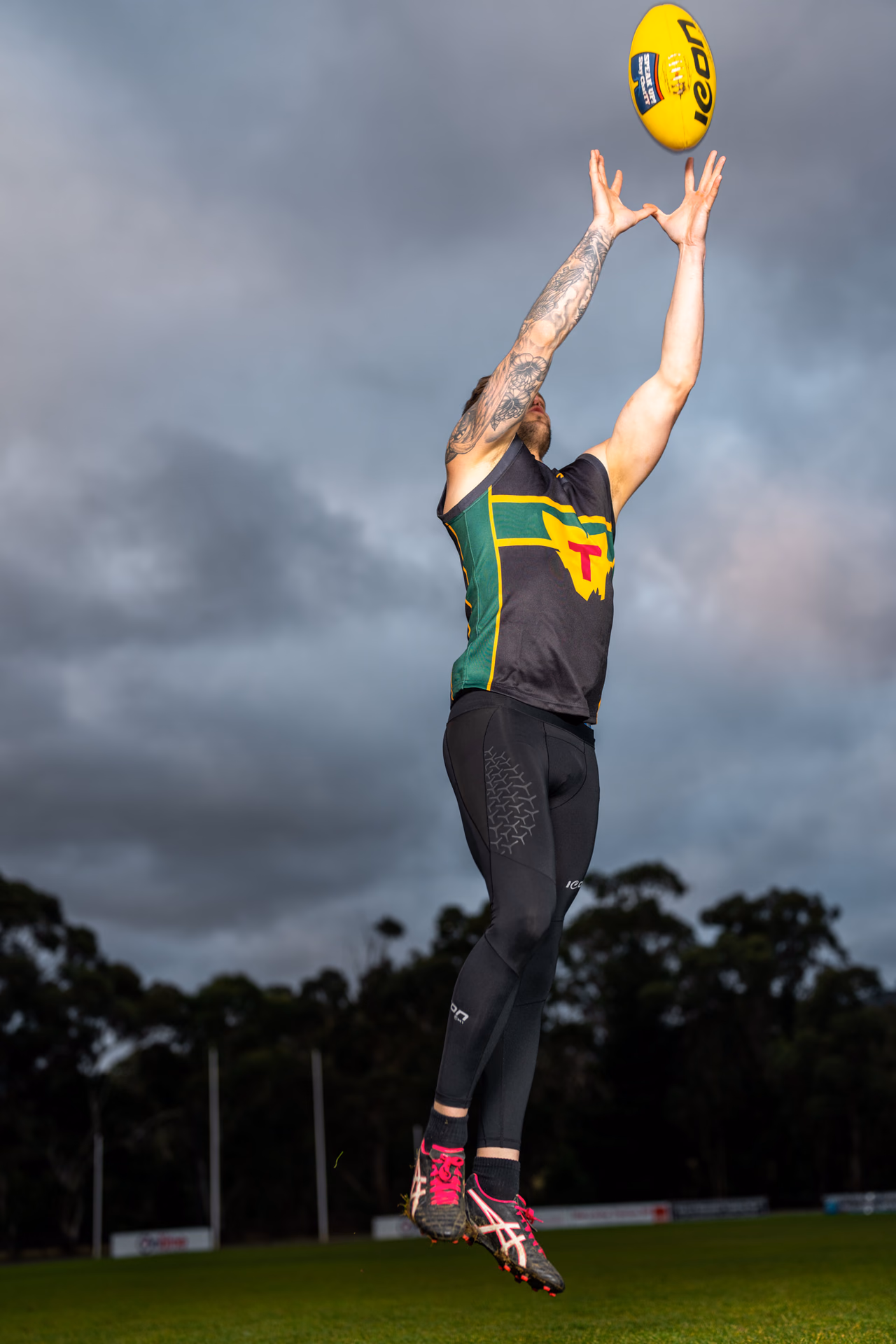Footballer reaching for a ball in black and green Icon Sports kit
